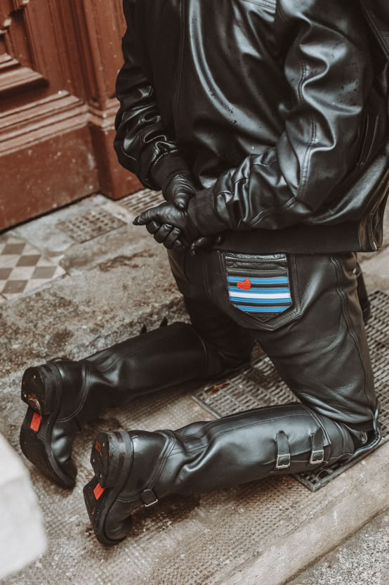 A soldier in vintage uniform sits by a tent with military equipment outdoors.